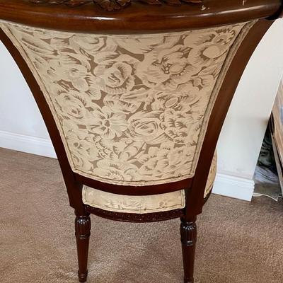 Beige upholstered ornately carved wooden chair