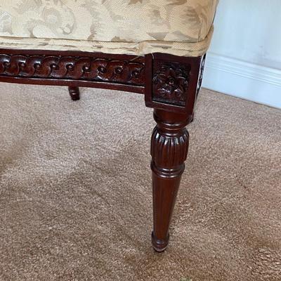 Beige upholstered ornately carved wooden chair