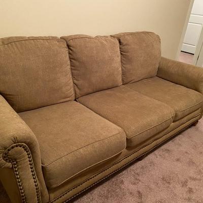 Tan upholstered sofa with nail-head trim