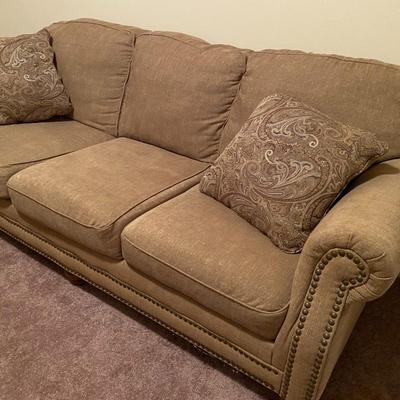 Tan upholstered sofa with nail-head trim
