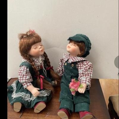 Boy and Girl Porcelain Dolls with Kissing faces. In like new condition. Matching outfits.