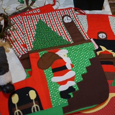 HOLIDAY GROUPING. HAND CRAFTED SANTA IN FLANNEL SHIRT CARRYING BOUGHS OF GREENS AND GIFTS SITS ON CERAMIC RED TRUCK / THREE HAND CRAFTED...
