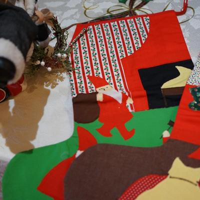 HOLIDAY GROUPING. HAND CRAFTED SANTA IN FLANNEL SHIRT CARRYING BOUGHS OF GREENS AND GIFTS SITS ON CERAMIC RED TRUCK / THREE HAND CRAFTED...