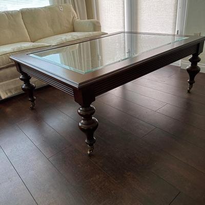 LOT 308. ETHAN ALLEN GLASS AND WOOD COFFEE TABLE ON CASTERS