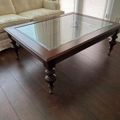 LOT 308. ETHAN ALLEN GLASS AND WOOD COFFEE TABLE ON CASTERS