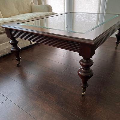LOT 308. ETHAN ALLEN GLASS AND WOOD COFFEE TABLE ON CASTERS