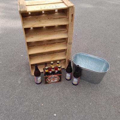 Wooden crate with Metal handled oval Ice tub, tall Fat tire beer bottles and Christmas brew 6 pack bottles.