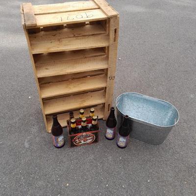 Wooden crate with Metal handled oval Ice tub, tall Fat tire beer bottles and Christmas brew 6 pack bottles.