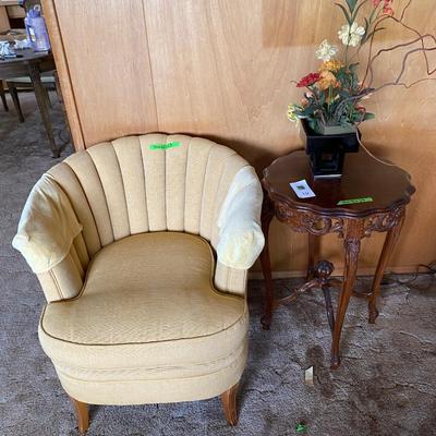 Yellow club chair with small carved wood side table
