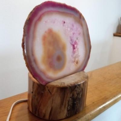 LIGHTED AGATE SLICE RESTING ON A PIECE OF TREE TRUNK