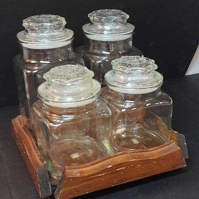 Four-piece lidded glass canister set on wooden Lazy Susan with vintage salt & pepper bear shakers