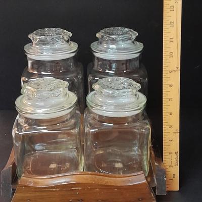 Four-piece lidded glass canister set on wooden Lazy Susan with vintage salt & pepper bear shakers