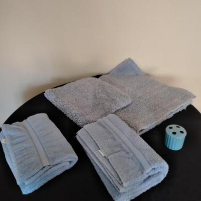 Two throw rugs, two towels and a toothbrush holder