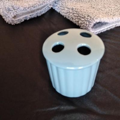 Two throw rugs, two towels and a toothbrush holder