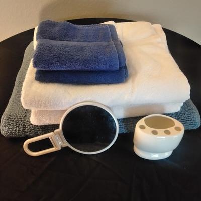 Two bath rugs, towels, hand towels, toothbrush holder and handheld mirror
