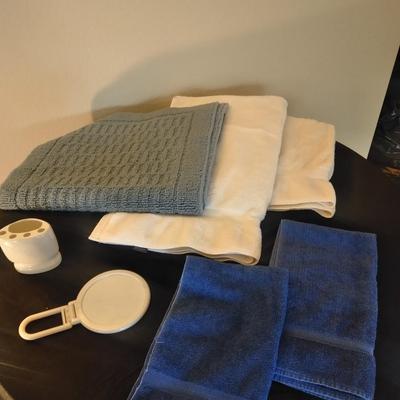 Two bath rugs, towels, hand towels, toothbrush holder and handheld mirror