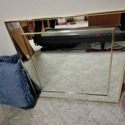 Two throw pillows and a gold framed wall mirror
