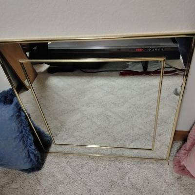 Two throw pillows and a gold framed wall mirror