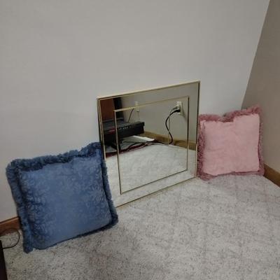 Two throw pillows and a gold framed wall mirror