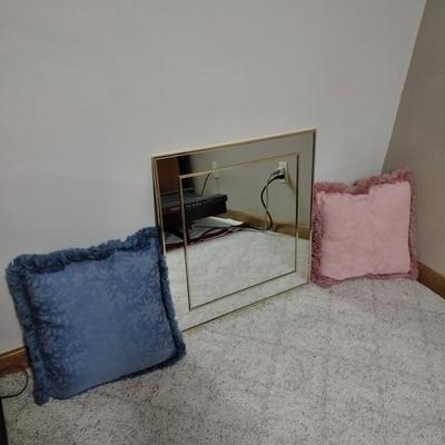 Two throw pillows and a gold framed wall mirror