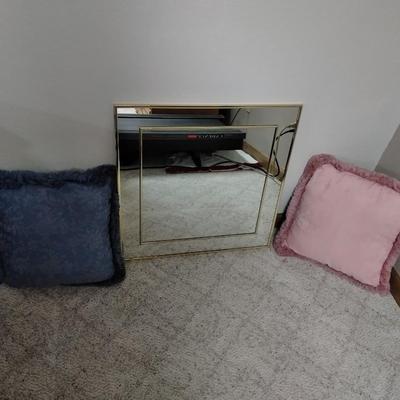 Two throw pillows and a gold framed wall mirror