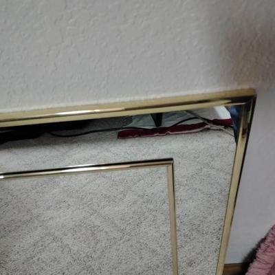 Two throw pillows and a gold framed wall mirror