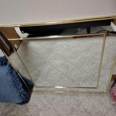 Two throw pillows and a gold framed wall mirror