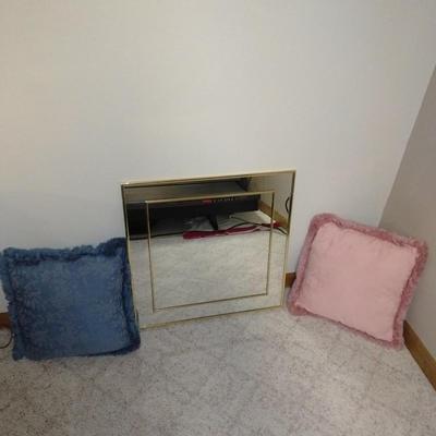 Two throw pillows and a gold framed wall mirror