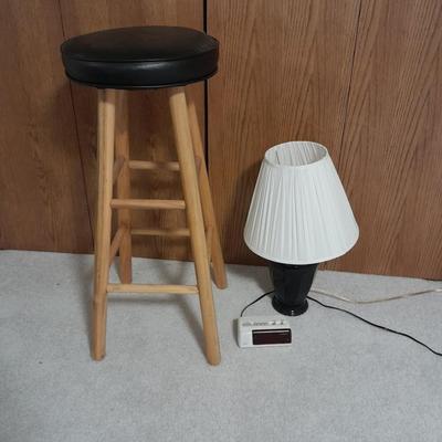 Cushioned wooden bar stool small lamp and an alarm clock