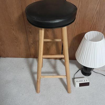 Cushioned wooden bar stool small lamp and an alarm clock