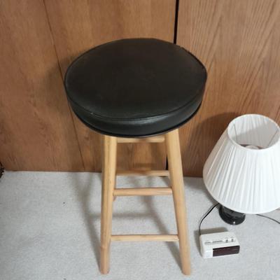 Cushioned wooden bar stool small lamp and an alarm clock