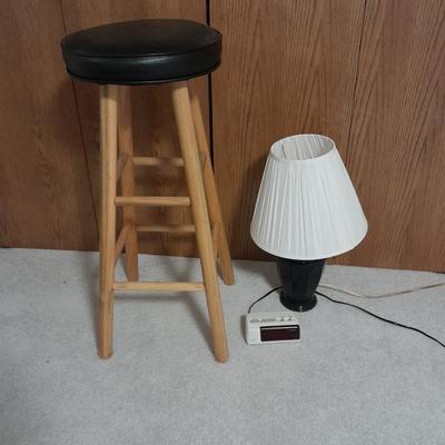 Cushioned wooden bar stool small lamp and an alarm clock