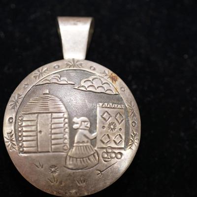 NAVAJO SILVER WORKED PENDANT OF RUG WEAVER ON ONE SIDE BLACK ONYX DISC ON OTHER.