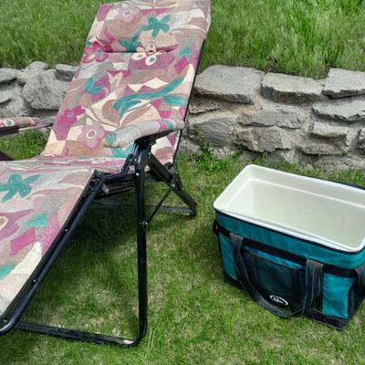 Folding metal framed cushioned chair and a cooler.