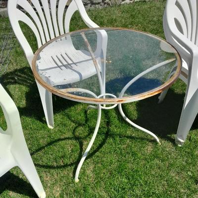 Small glass topped table with 4 plastic patio chairs