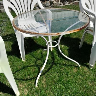 Small glass topped table with 4 plastic patio chairs