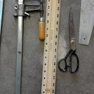 Two clamps, hand saw, claw bar, and a large ruler