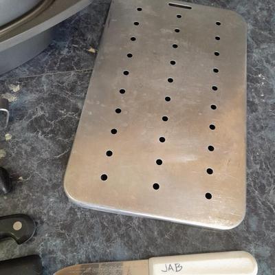 Lidded baking pan with an assortment of knives and electronic thermometer fork