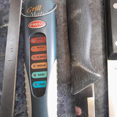Lidded baking pan with an assortment of knives and electronic thermometer fork
