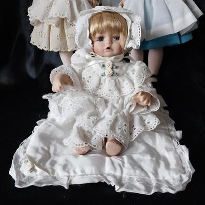 THREE PORCELIAN DOLLS WITH  HAND SEWN OUTFITS