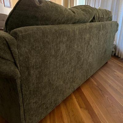Dark green upholstered loveseat with wooden accents