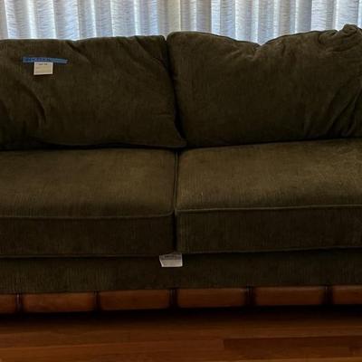 Dark green upholstered loveseat with wooden accents