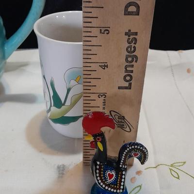 Blue pitcher with bee, coffee mug, metal rooster decor, and glasses with embroidered linen table runner