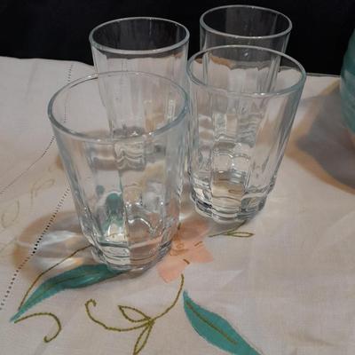 Blue pitcher with bee, coffee mug, metal rooster decor, and glasses with embroidered linen table runner