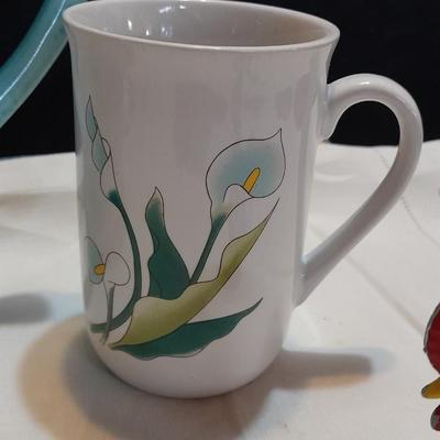 Blue pitcher with bee, coffee mug, metal rooster decor, and glasses with embroidered linen table runner