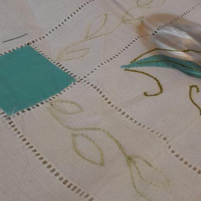 Blue pitcher with bee, coffee mug, metal rooster decor, and glasses with embroidered linen table runner