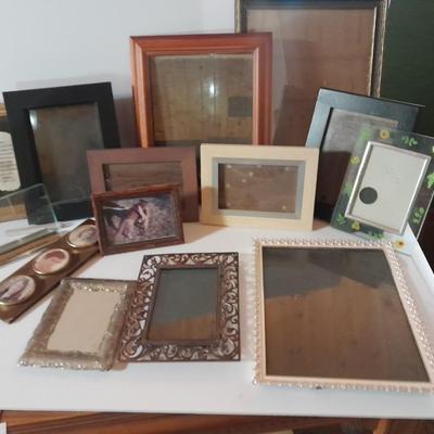 Variety of picture frames, some wood, some metal