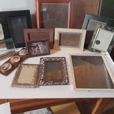 Variety of picture frames, some wood, some metal