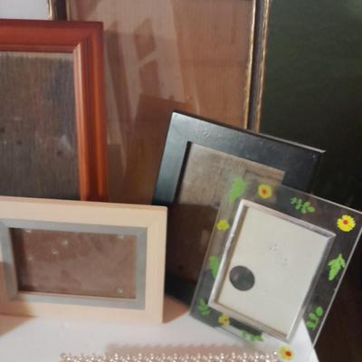 Variety of picture frames, some wood, some metal