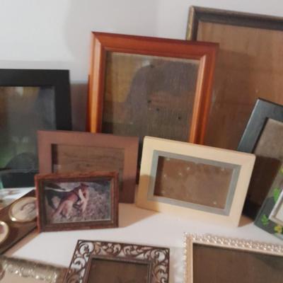 Variety of picture frames, some wood, some metal